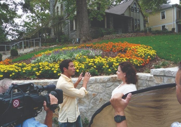 Barb-Shadomy_Stonehurst_Ground_Breakers_HGTV-696x522 news camera focused on man and woman in front of Stonehurst Place