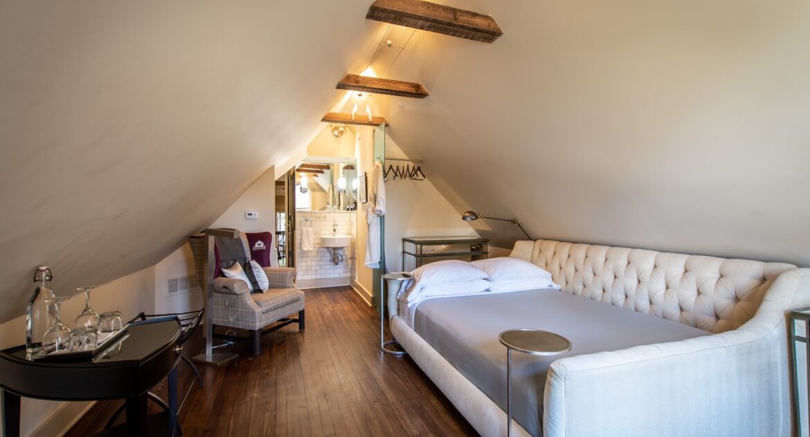 Eaves room with vaulted ceilings and a table with wine and water glasses on top