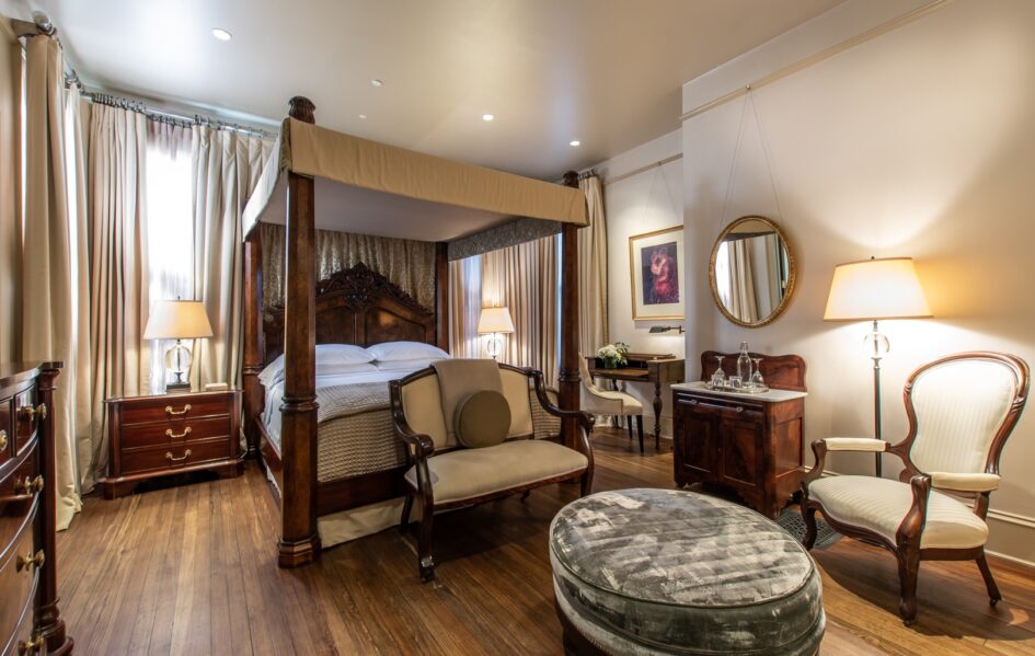 Hinman Suite-Stonehurst Pl-20 Hinman Suite with canopy bed and a sitting area with a velvet ottoman