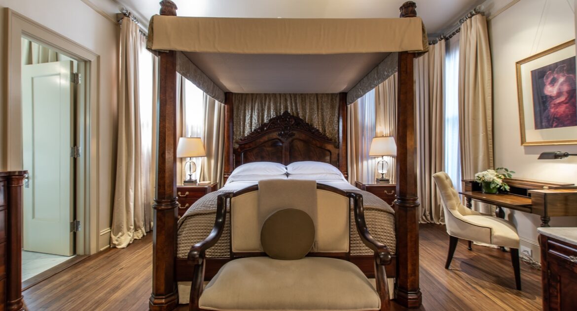 Hinman Suite canopy bed with a wood armed love seat