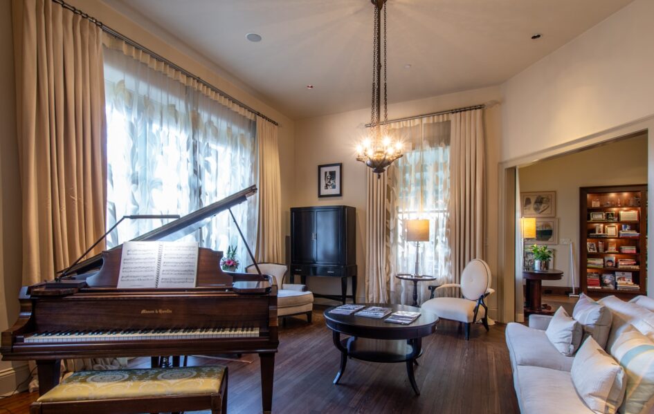 Piano room with sitting area and a round wood coffee table with magazines on top