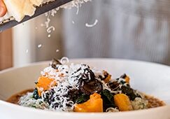 pecorino cheese being grated over roasted root vegetables