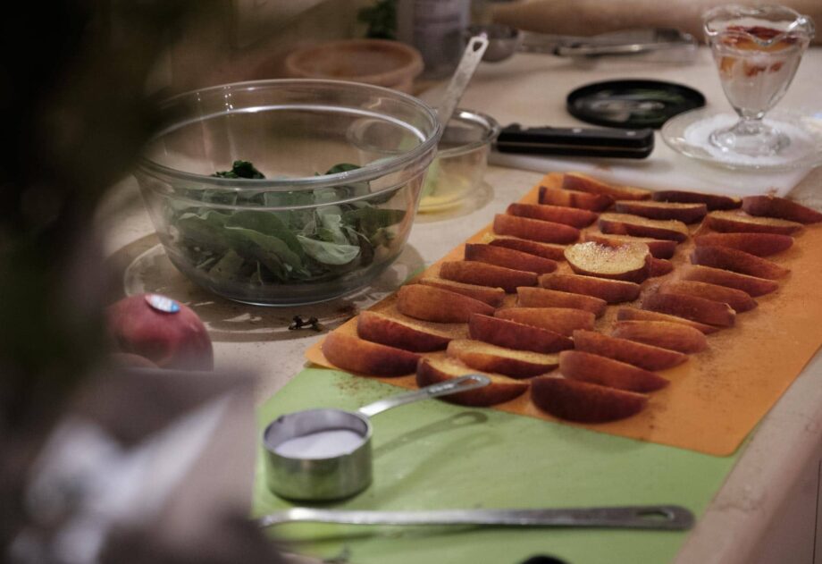 sliced peaches on orange cutting board spinach in glass bowl at Stonehurst Place