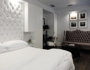 Stedman Suite bed and velvet sofa to the side with four colored portraits above in Stonehurst Place