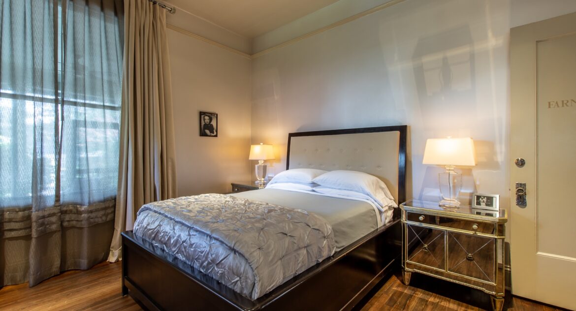 Farnsworth room with two mirroed nightstands and a bed with silver metallic comforter