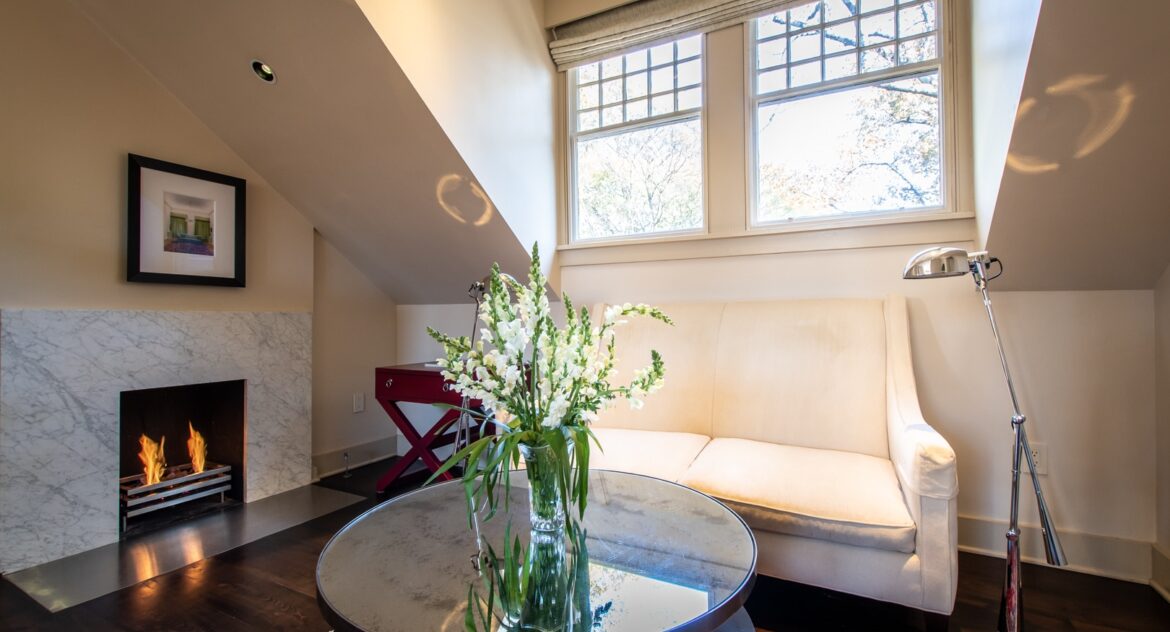Master Suite sitting area with fireplace and a mirrored coffee table with a vase with flowers on top