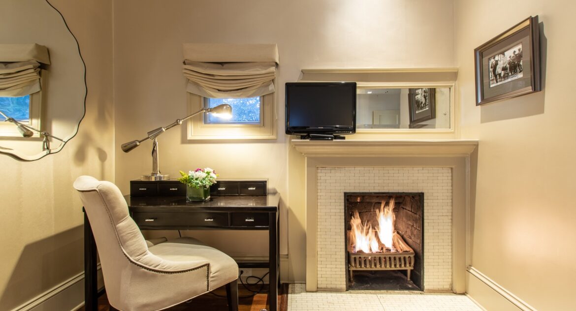 Piedmont room with fireplace and a arm chair and desk to the side